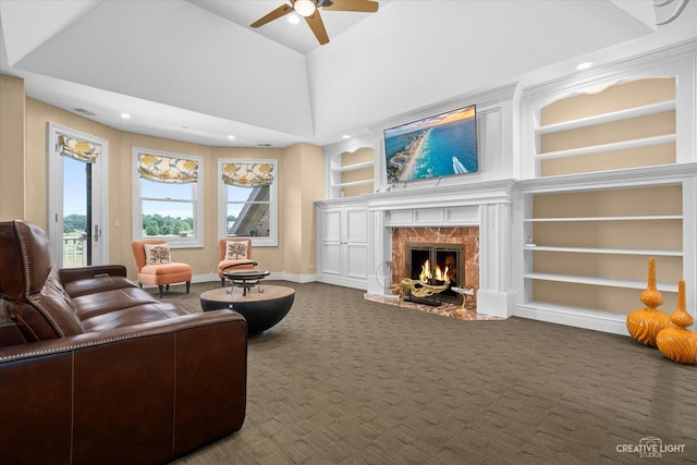 carpeted living room with ceiling fan, built in shelves, visible vents, a high end fireplace, and baseboards