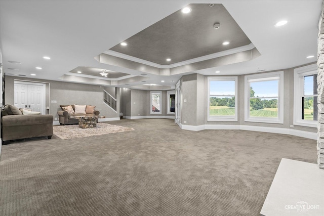 living area featuring a raised ceiling, stairway, ornamental molding, carpet flooring, and baseboards