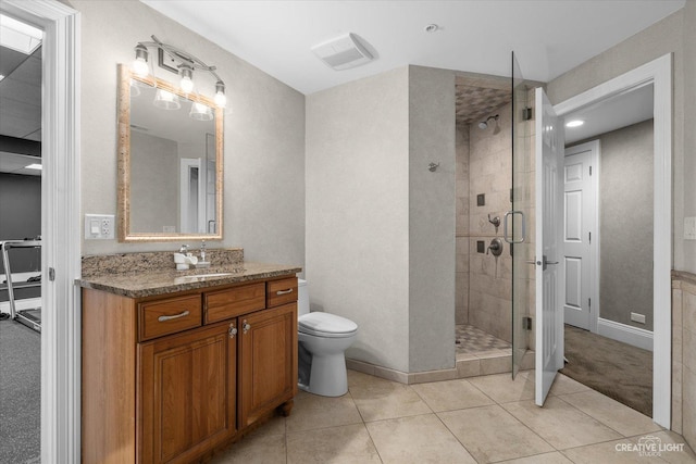 bathroom featuring toilet, a stall shower, vanity, baseboards, and tile patterned floors