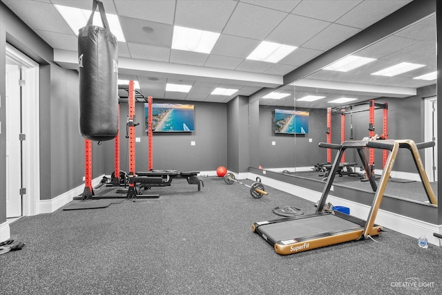 exercise area featuring baseboards and a drop ceiling