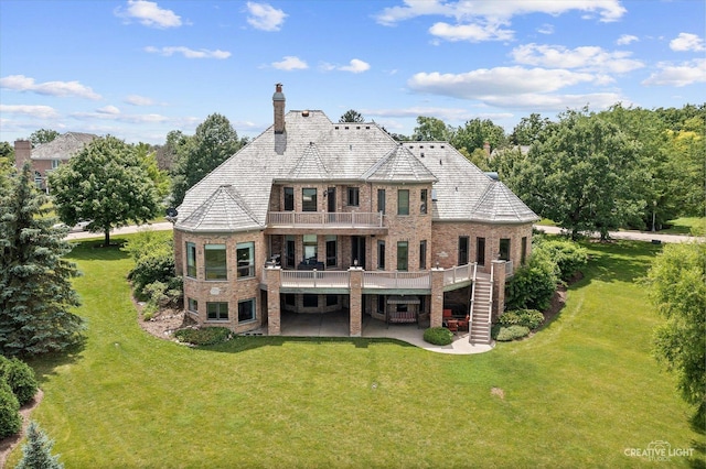 rear view of house featuring a balcony, a patio area, stairway, and a lawn