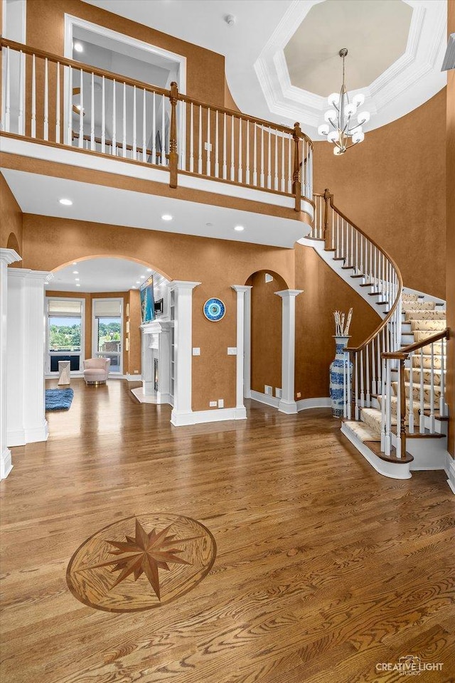 interior space featuring an inviting chandelier, arched walkways, a raised ceiling, and wood finished floors