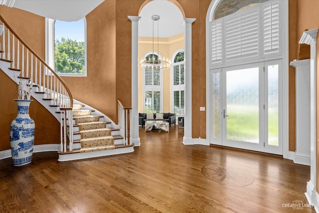 foyer with a notable chandelier, a high ceiling, stairway, and wood finished floors