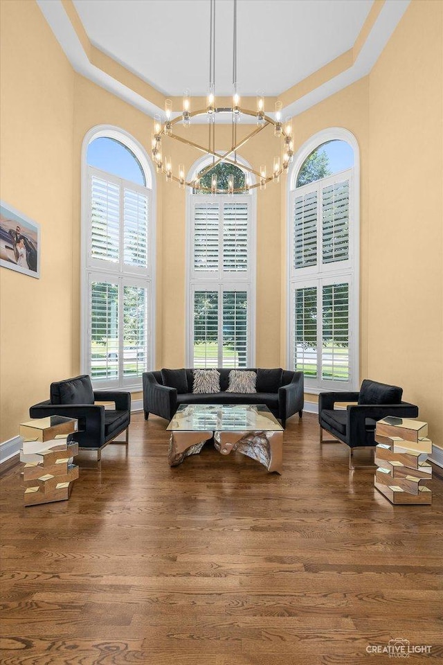 living area featuring wood finished floors, a towering ceiling, and baseboards