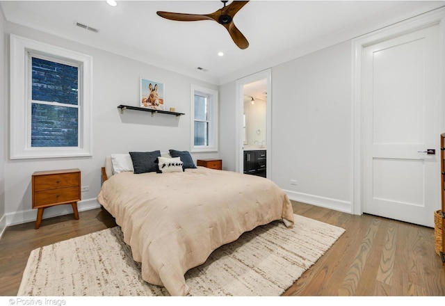 bedroom with baseboards, visible vents, wood finished floors, ensuite bathroom, and recessed lighting