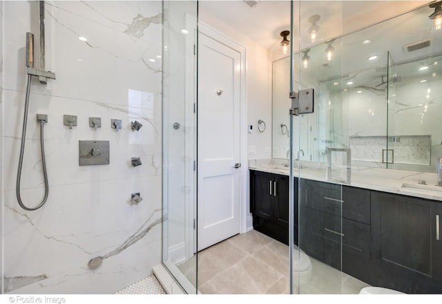 bathroom with double vanity, a marble finish shower, visible vents, and a sink