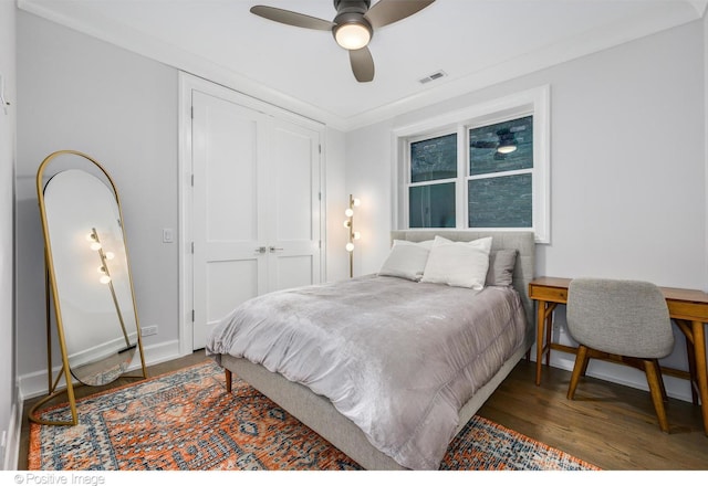 bedroom featuring wood finished floors, a ceiling fan, visible vents, baseboards, and a closet