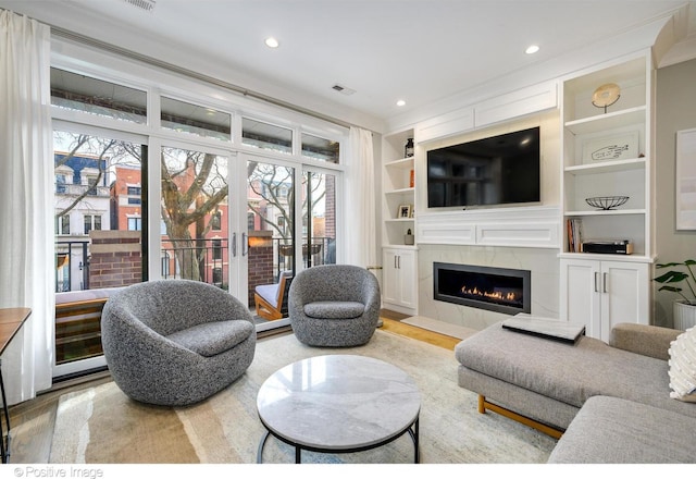 living area featuring recessed lighting, wood finished floors, a fireplace with flush hearth, visible vents, and built in features