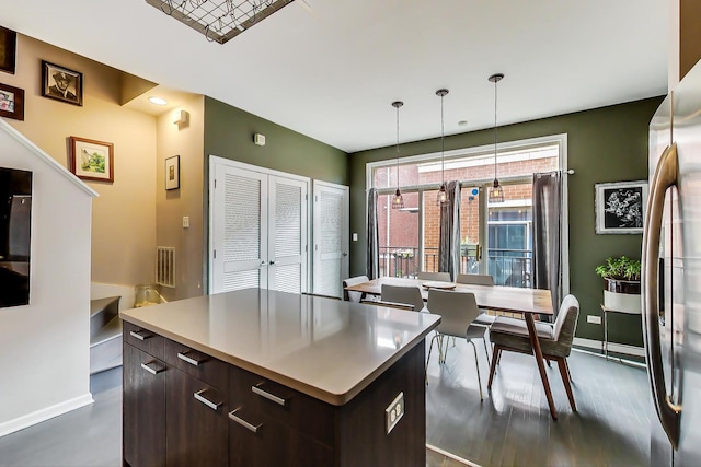 kitchen with modern cabinets, a kitchen island, freestanding refrigerator, dark brown cabinetry, and baseboards