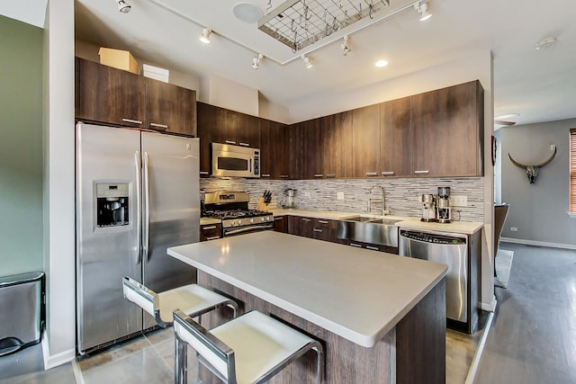 kitchen featuring a sink, decorative backsplash, stainless steel appliances, dark brown cabinets, and a center island