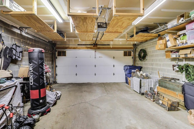 garage with a garage door opener and concrete block wall