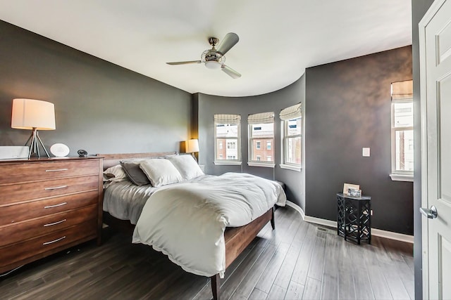 bedroom with ceiling fan, dark wood-type flooring, and baseboards