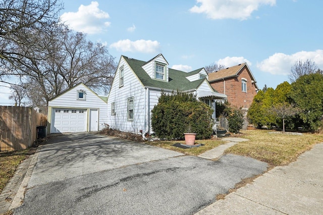 view of front of house featuring fence, aphalt driveway, a front yard, a garage, and an outbuilding