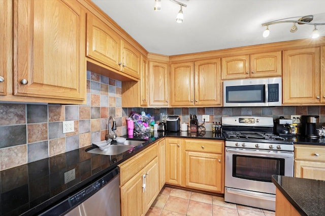 kitchen featuring a sink, light tile patterned floors, backsplash, and stainless steel appliances