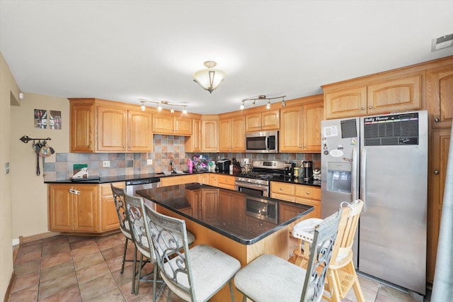 kitchen featuring a kitchen island, a breakfast bar, decorative backsplash, stainless steel appliances, and a sink