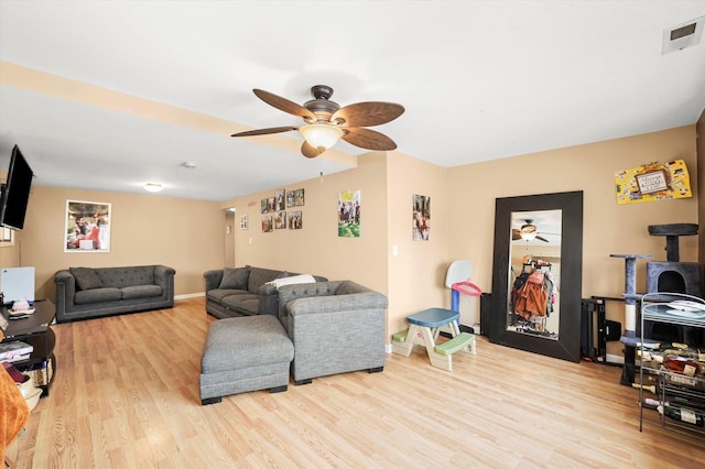 living area with baseboards, wood finished floors, visible vents, and ceiling fan