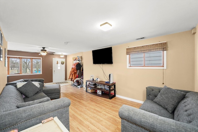 living area featuring visible vents, light wood-style floors, and baseboards