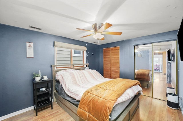 bedroom featuring a ceiling fan, light wood-style floors, visible vents, and baseboards