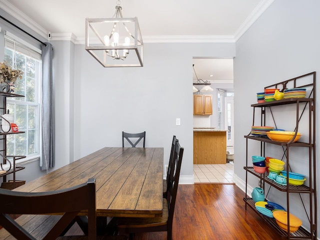 dining area with ornamental molding, dark wood-type flooring, baseboards, and an inviting chandelier