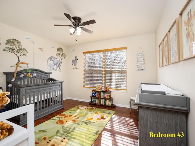 bedroom featuring a nursery area, wood finished floors, and baseboards