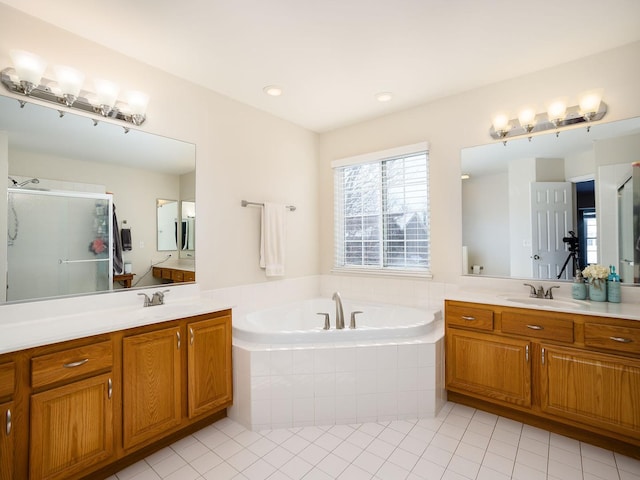 bathroom with a garden tub, two vanities, a sink, a shower stall, and tile patterned floors