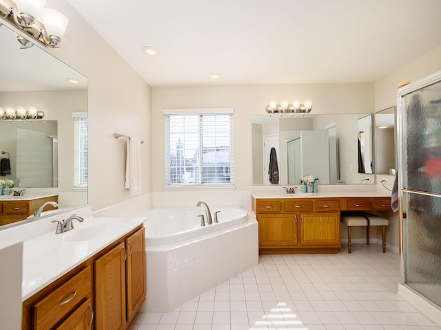 bathroom with a garden tub, a shower stall, two vanities, and a sink