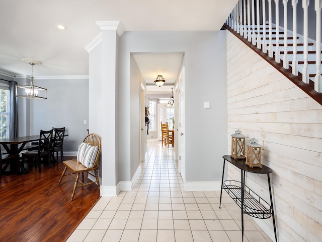 hallway featuring an inviting chandelier, baseboards, ornamental molding, and light tile patterned flooring