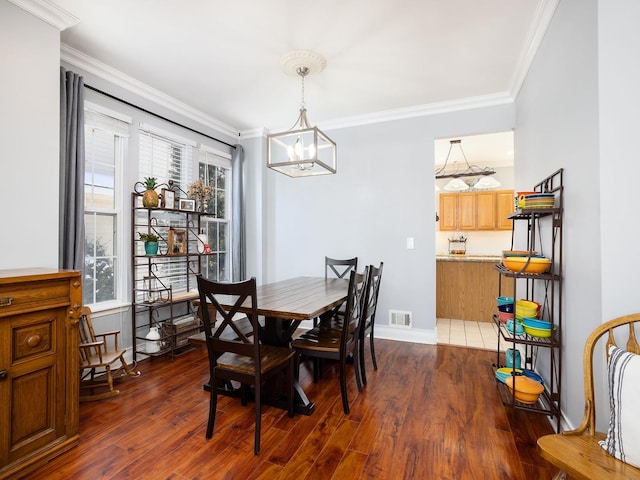 dining area with baseboards, visible vents, dark wood-type flooring, an inviting chandelier, and crown molding