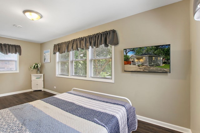 bedroom with multiple windows, baseboards, and wood finished floors