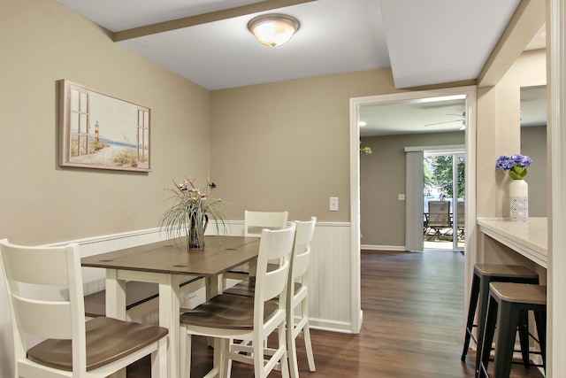 dining room featuring a wainscoted wall and dark wood-type flooring