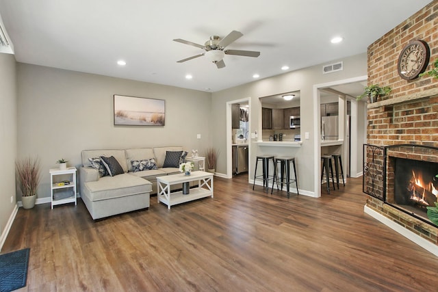 living room featuring a brick fireplace, visible vents, wood finished floors, and recessed lighting