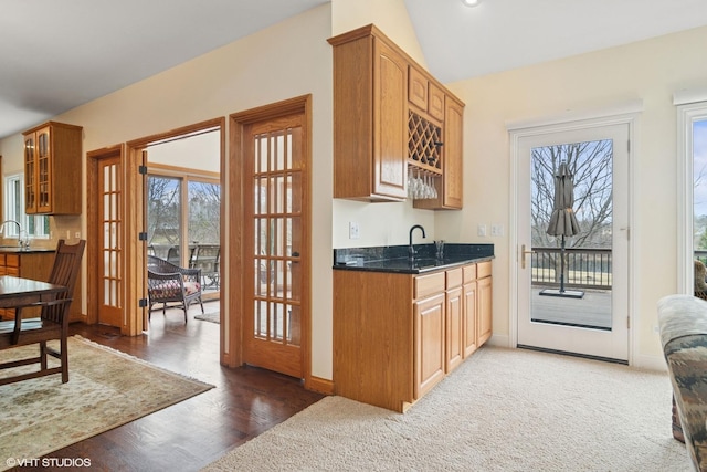 kitchen featuring vaulted ceiling, french doors, a sink, glass insert cabinets, and baseboards