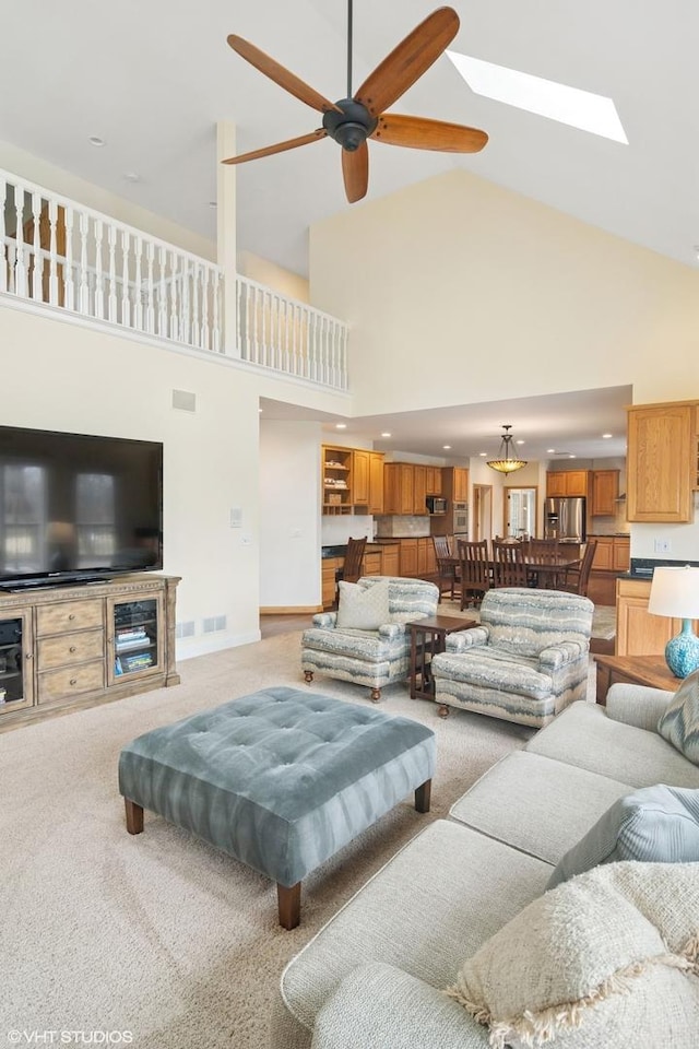 living area featuring light carpet, visible vents, high vaulted ceiling, and a ceiling fan