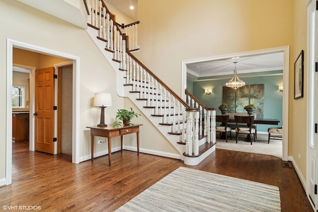 foyer entrance featuring a high ceiling, stairs, wood finished floors, and baseboards