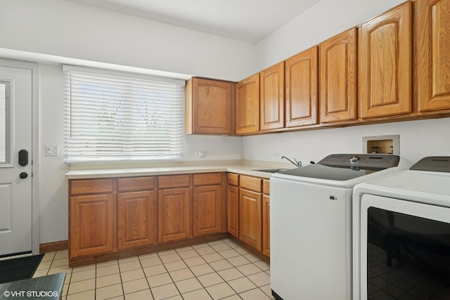 laundry area featuring light tile patterned floors, a sink, cabinet space, and separate washer and dryer