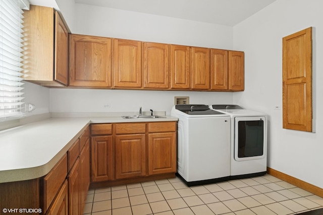 clothes washing area with light tile patterned floors, baseboards, a sink, cabinet space, and washer and dryer