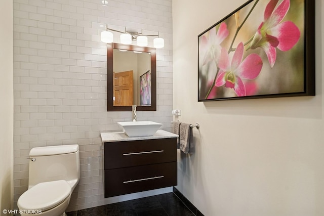 bathroom with toilet, vanity, and tile walls