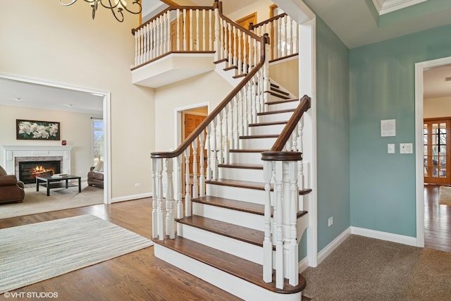 stairway with a high end fireplace, wood finished floors, baseboards, and a wealth of natural light