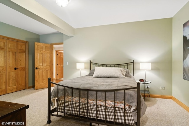 carpeted bedroom featuring baseboards and beamed ceiling