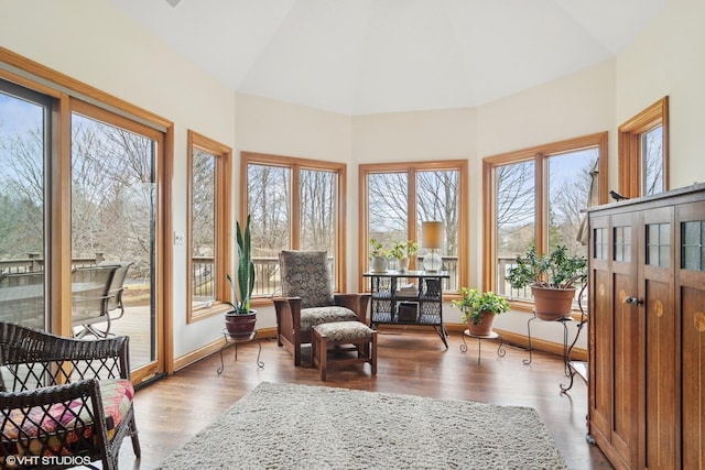sunroom / solarium with baseboards, wood finished floors, and vaulted ceiling