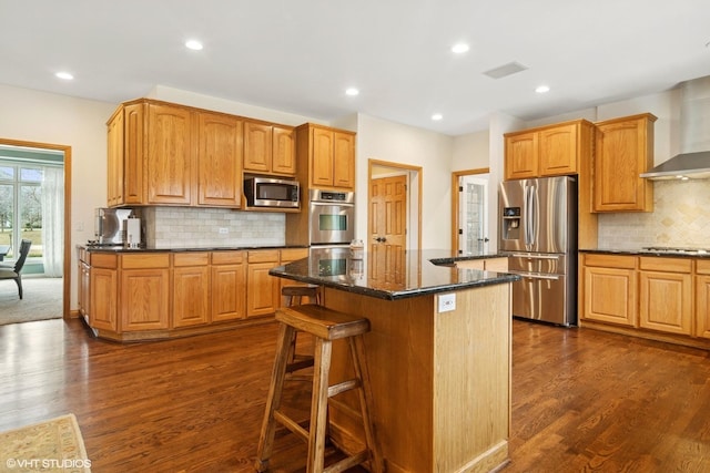 kitchen with dark stone counters, dark wood-style flooring, a kitchen island, and stainless steel appliances
