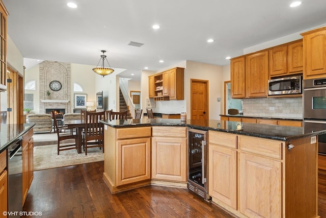 kitchen featuring dark stone counters, wine cooler, dark wood finished floors, appliances with stainless steel finishes, and a center island