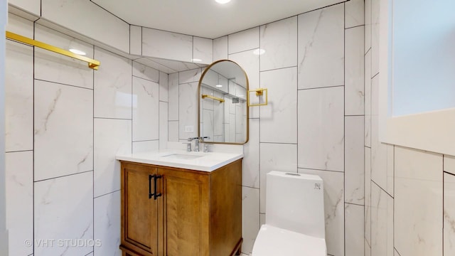 bathroom with toilet, tile walls, and vanity