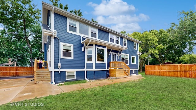 rear view of house featuring a lawn and fence