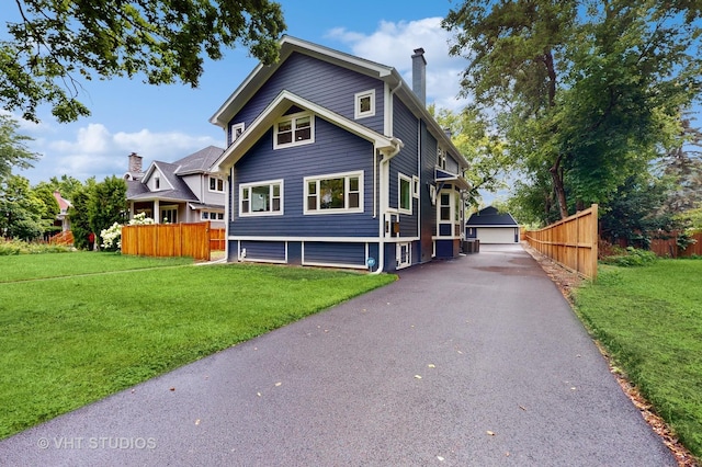 view of front of home with a front lawn, a chimney, an outdoor structure, and fence