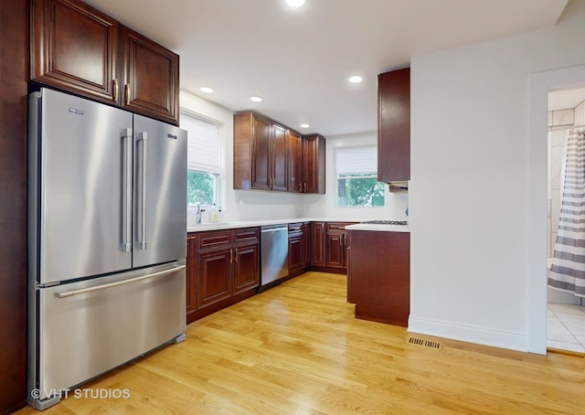 kitchen featuring a sink, visible vents, light wood-style floors, light countertops, and appliances with stainless steel finishes