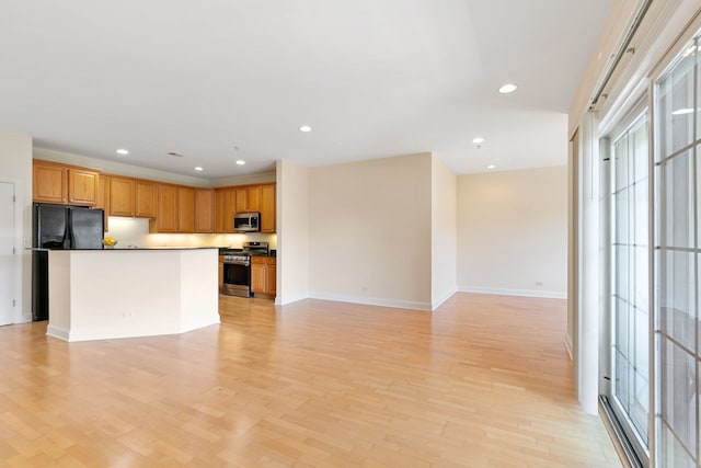 kitchen featuring open floor plan, appliances with stainless steel finishes, light wood-style flooring, and recessed lighting