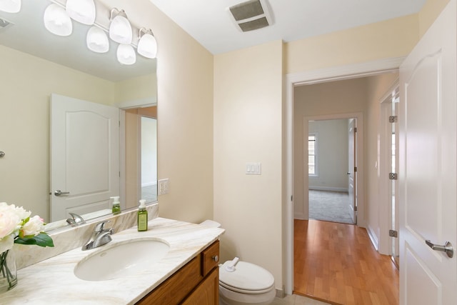 bathroom featuring toilet, wood finished floors, vanity, and visible vents