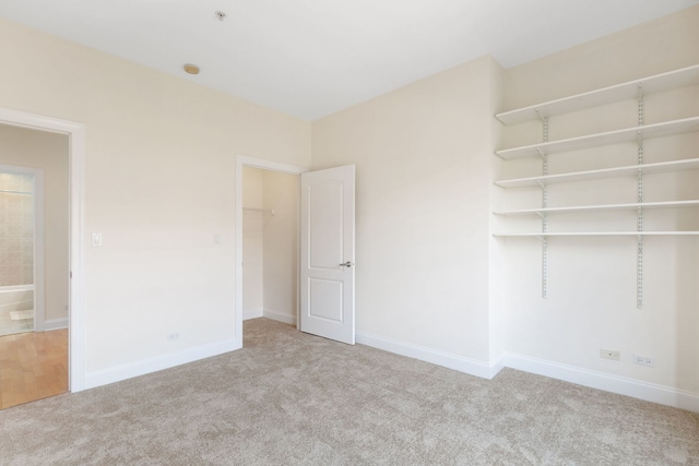 interior space featuring carpet floors, a walk in closet, a closet, and baseboards