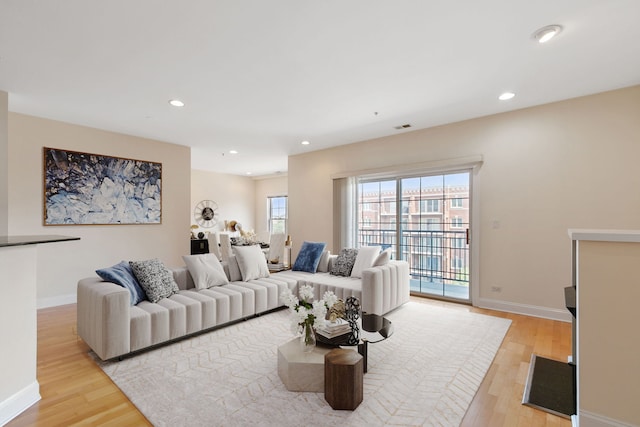 living room featuring light wood-style flooring, visible vents, baseboards, and recessed lighting